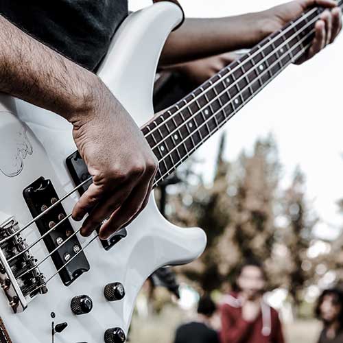 A close up of a bassist playing a white four string bass