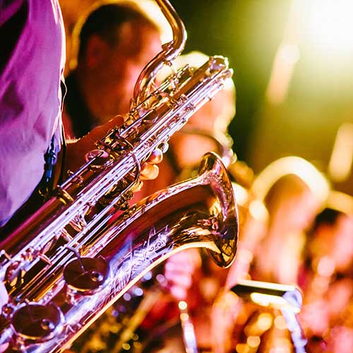 A close up of a baritone saxophone with the rest of a horn section in the background