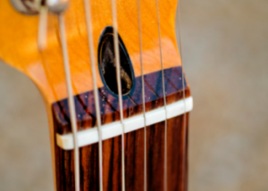 A plastic nut on an electric guitar