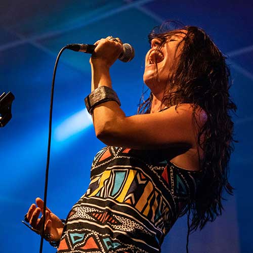 A woman with a microphone, belting a song on stage