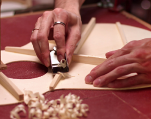 A luthier works on the braces of an acoustic guitar