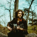 instructor, lennox with his guitar in the woods